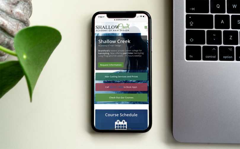 iPhone showing home page of the Shallow Creek Academy of Hair Design web site.