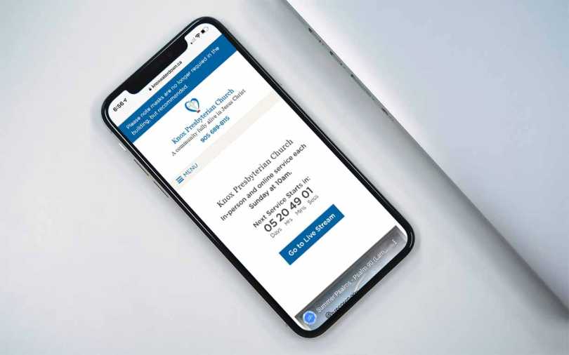 iPhone on a desk showing home page of the Knox Waterdown web site.